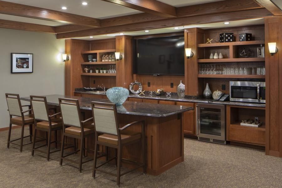 A stylish home bar setup with wooden cabinetry, a sleek countertop, and modern amenities.