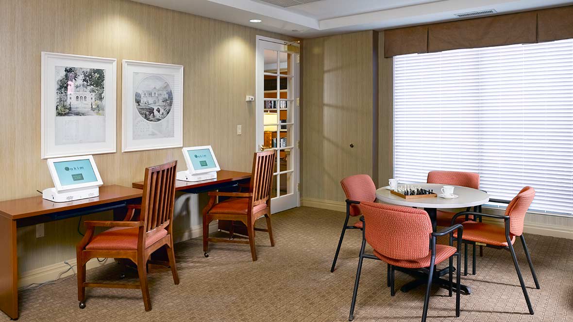 A well-appointed meeting room featuring comfortable chairs, a computer workstation, and ample natural light.