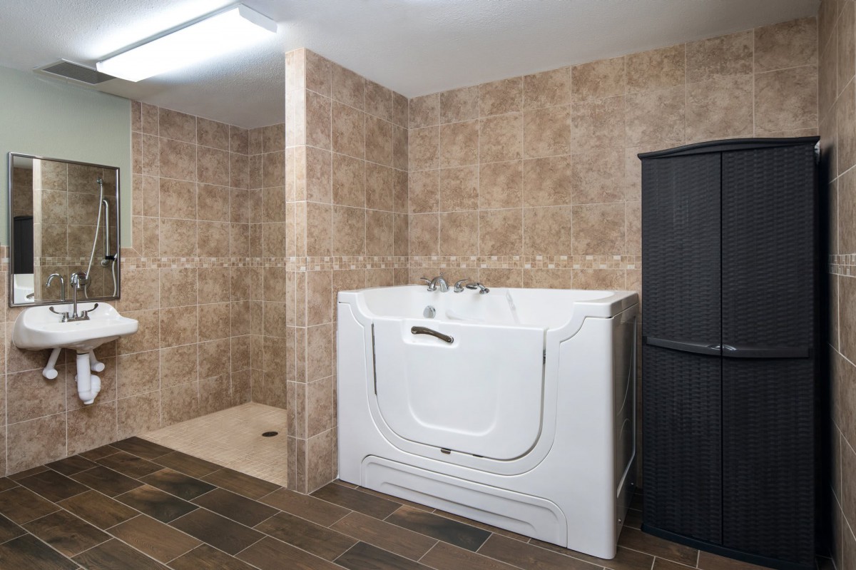 A modern bathroom featuring a walk-in tub and tiled walls.