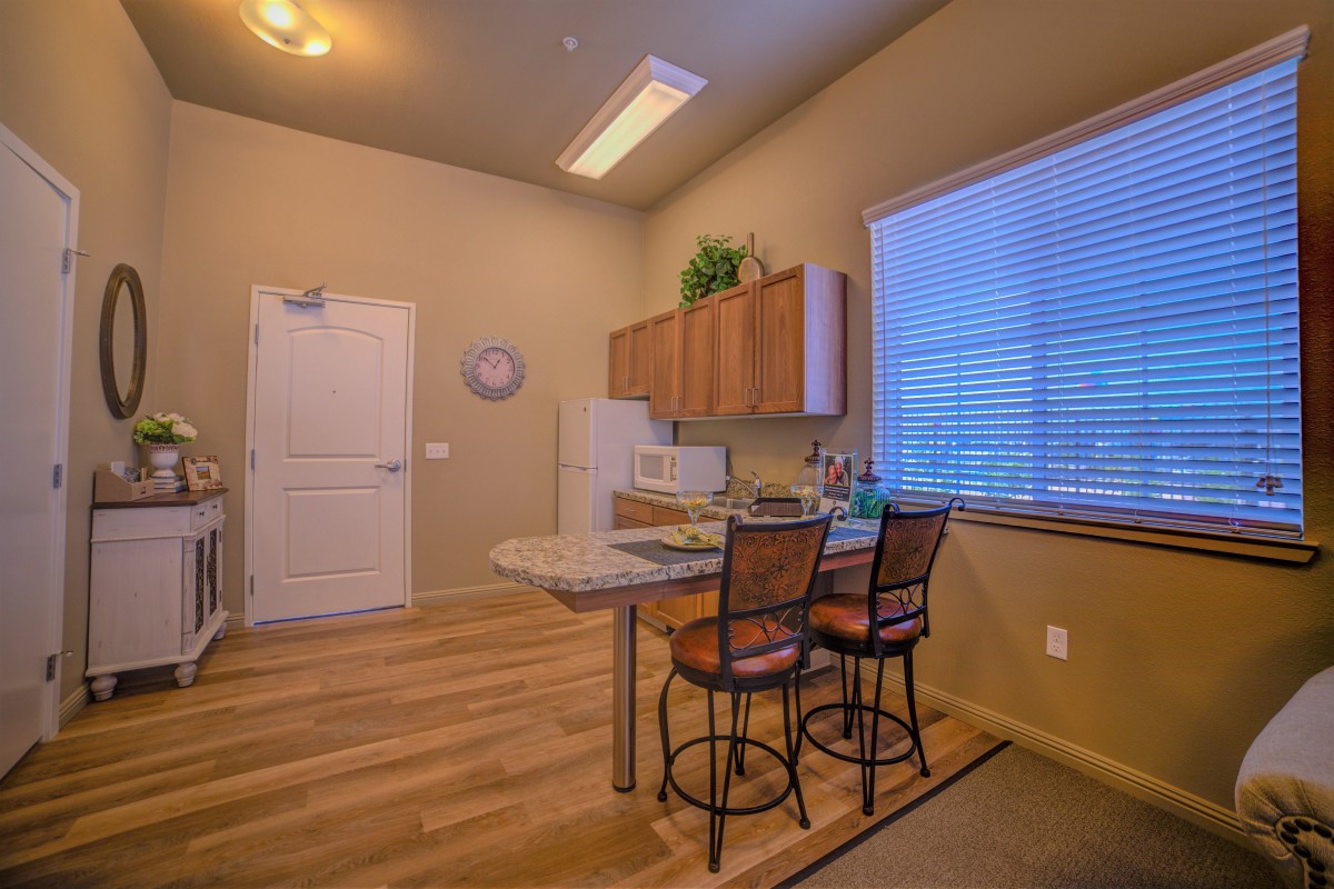 A modern kitchen interior featuring wooden flooring, bar stools, and stylish cabinets.