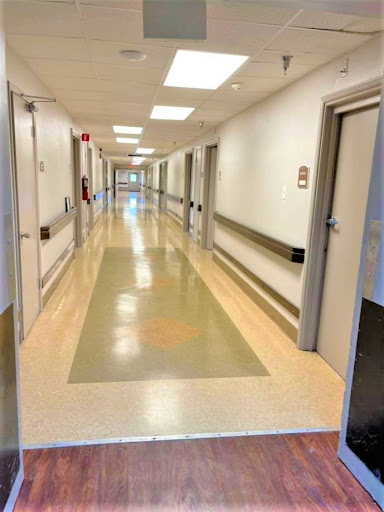A long, well-lit hallway in a hospital featuring clean floors and multiple doors.