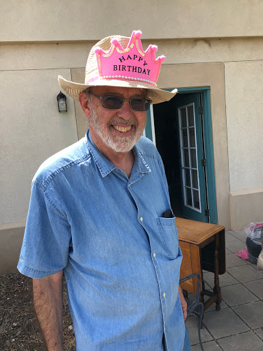 A cheerful man celebrating his birthday, wearing a festive pink hat.