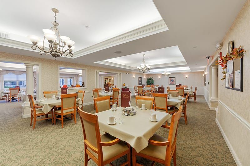 A spacious dining area with neatly arranged tables and elegant chandeliers.