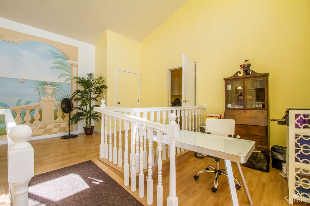 A bright and cozy home office space with a desk, chair, and bookshelf, complemented by yellow walls and wood flooring.
