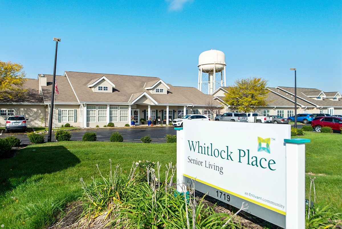 Exterior view of Whitlock Place Senior Living facility with a visible water tower in the background.