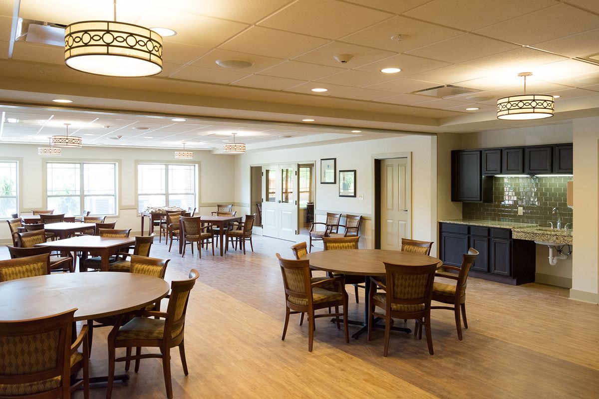 Spacious dining area with wooden tables and chairs, illuminated by ceiling lights.
