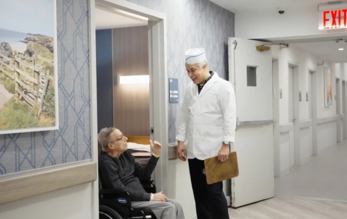 A doctor conversing with a patient in a wheelchair in a hospital corridor.
