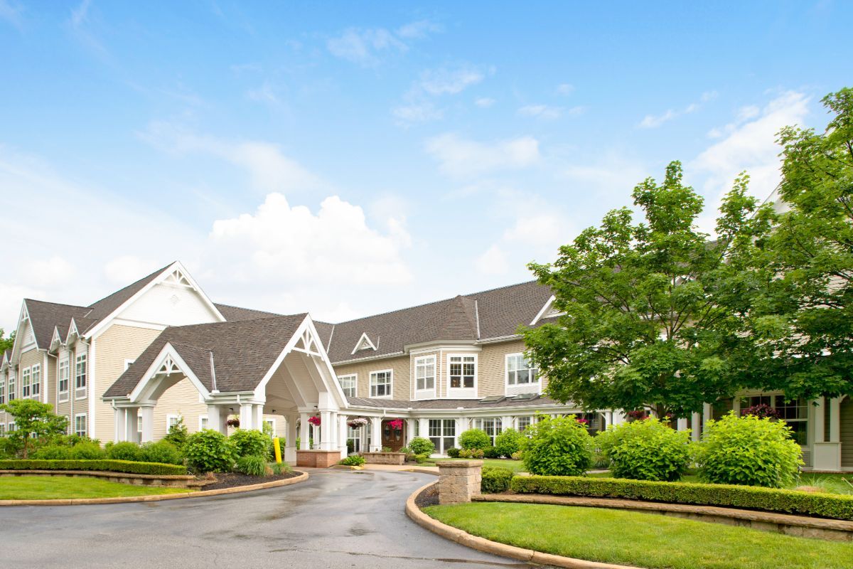 Elegant residential building with a circular driveway and lush greenery.