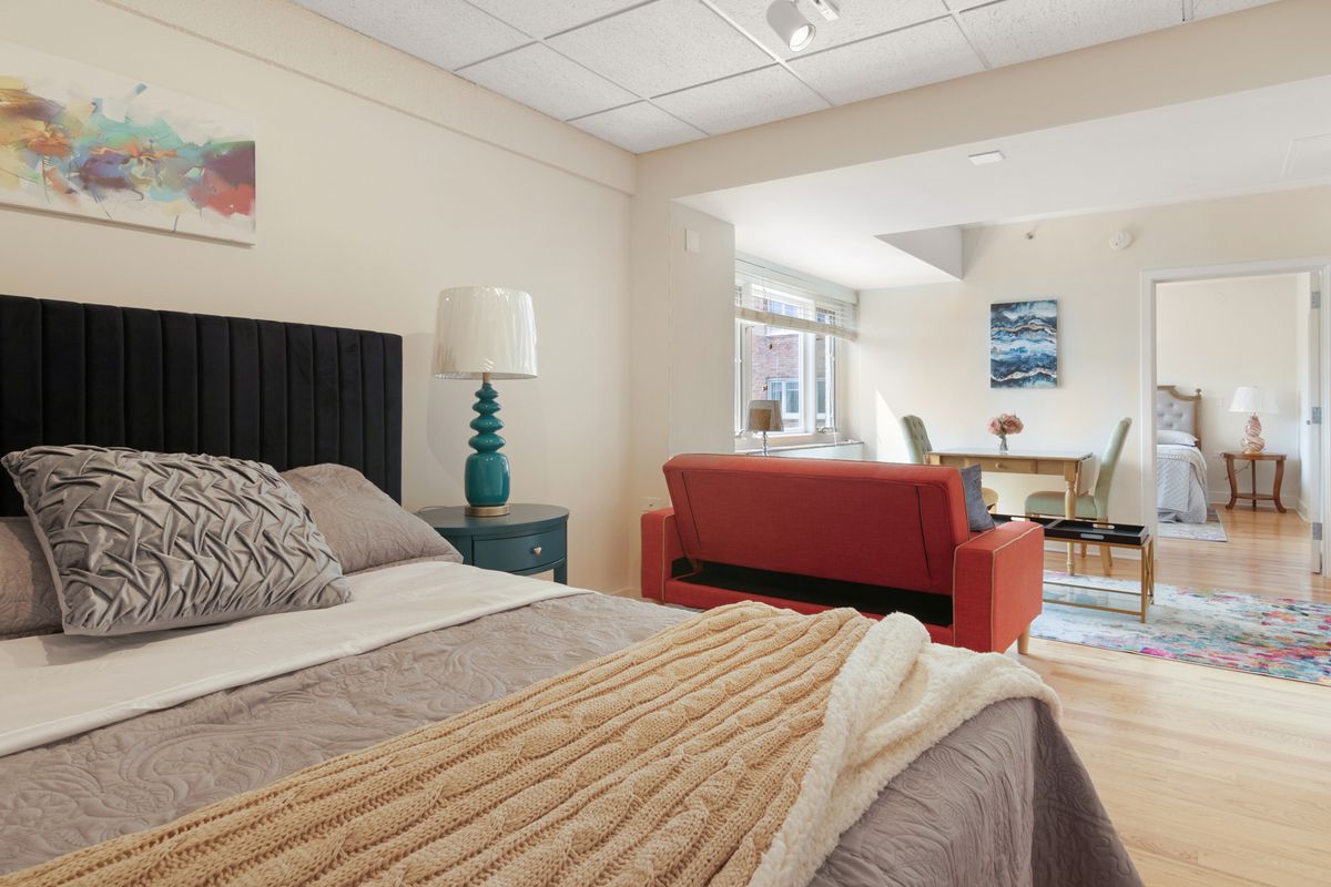A cozy bedroom with a comfortable bed, stylish lamp, and modern sofa.