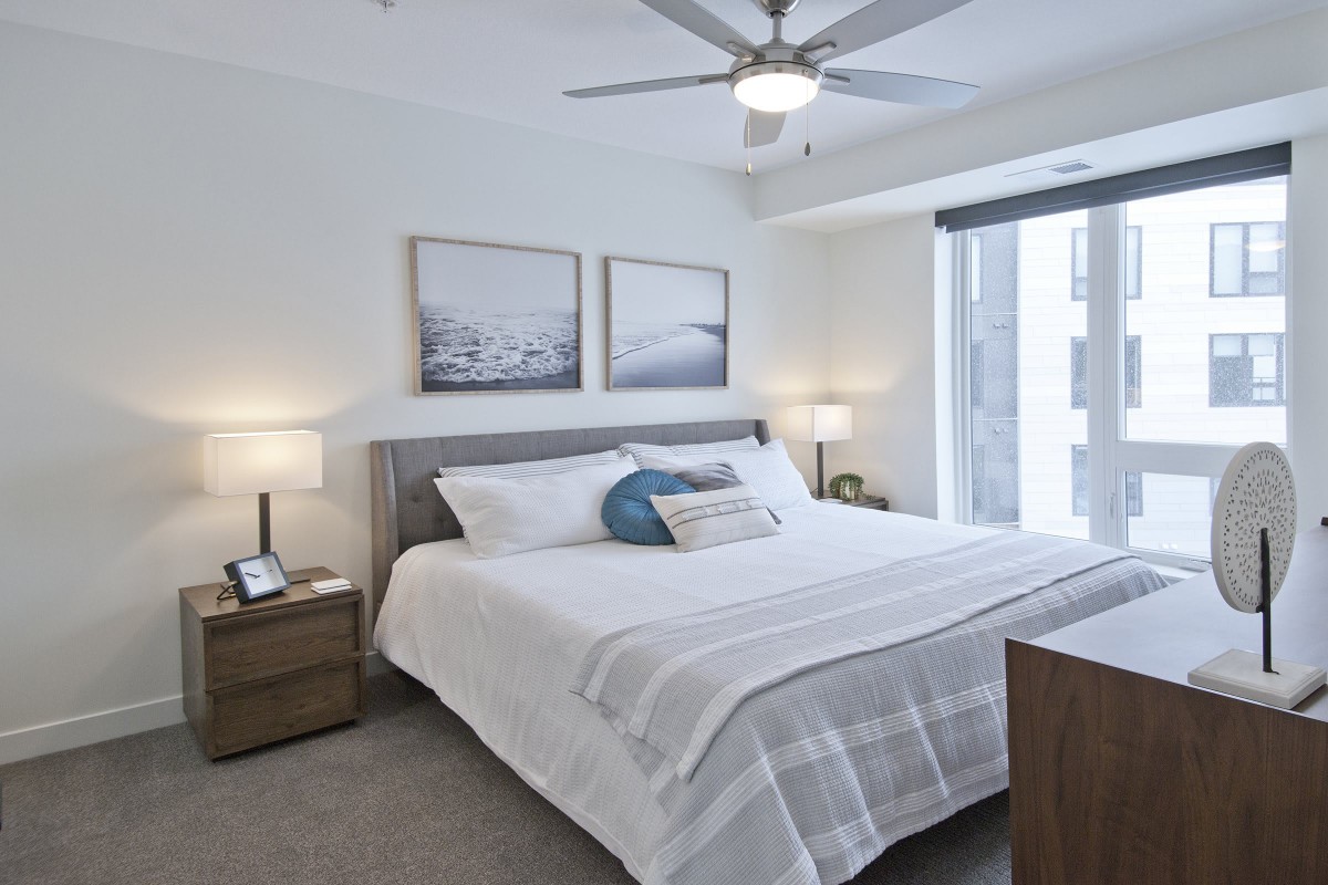 A modern, minimalist bedroom with a large bed, elegant decor, and ample natural lighting.
