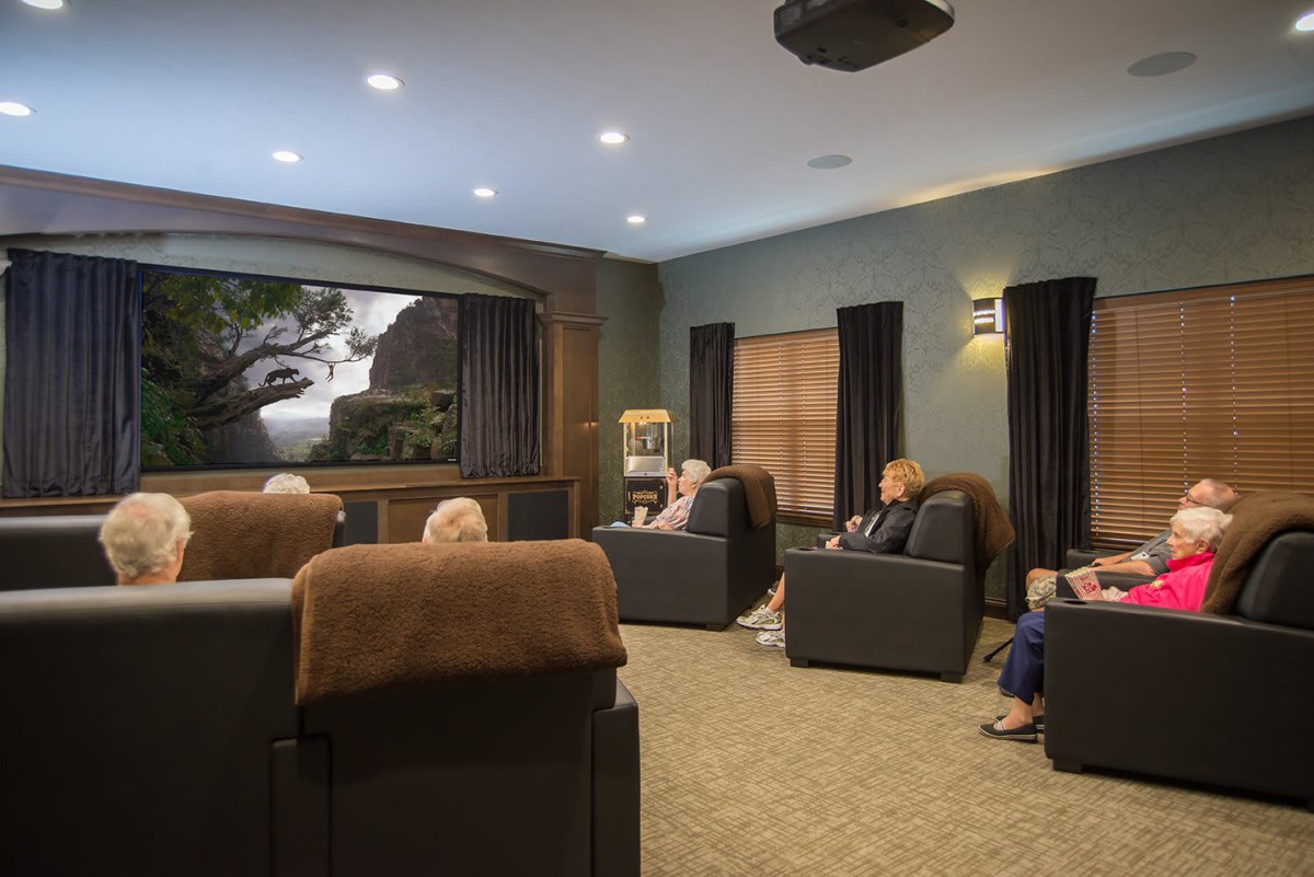 A group of people enjoying a movie in a cozy home theater with comfortable seating.