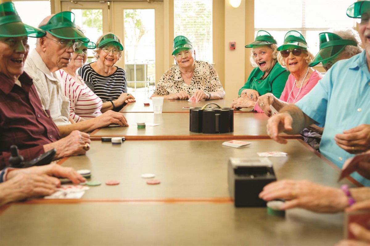 A group of seniors enjoying a card game together, wearing green hats.
