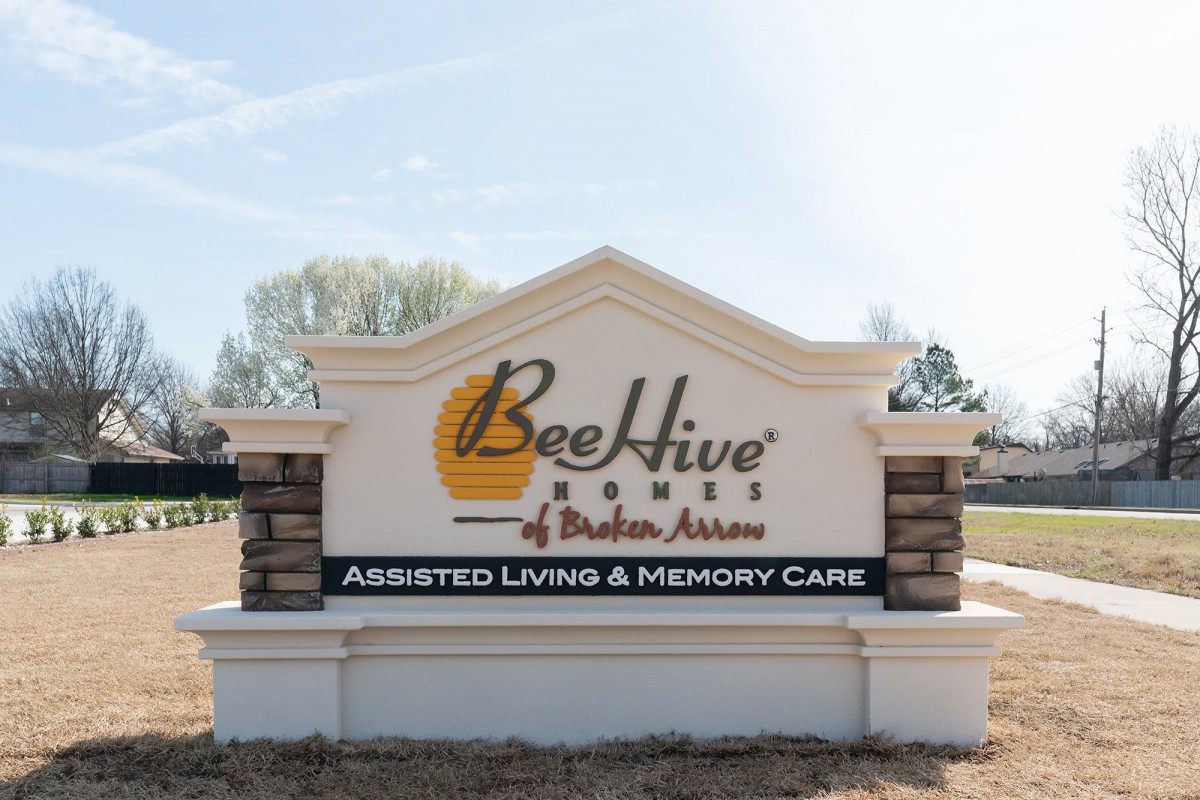 Outdoor sign for BeeHive Homes of Brighton Avenue, featuring assisted living and memory care services.