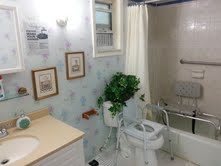A small bathroom with a toilet, sink, and bathtub featuring wall art and a potted plant.