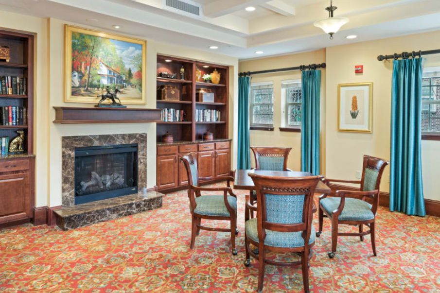 A cozy living room with a fireplace, bookshelves, and seating area.