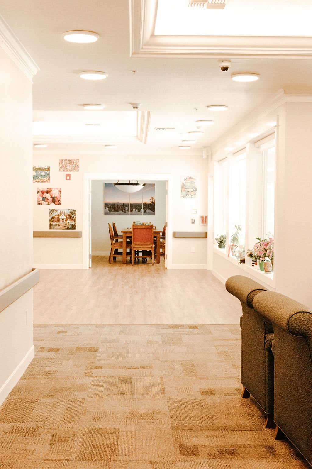 A bright, well-lit hallway leading to a cozy dining area with wooden furniture.