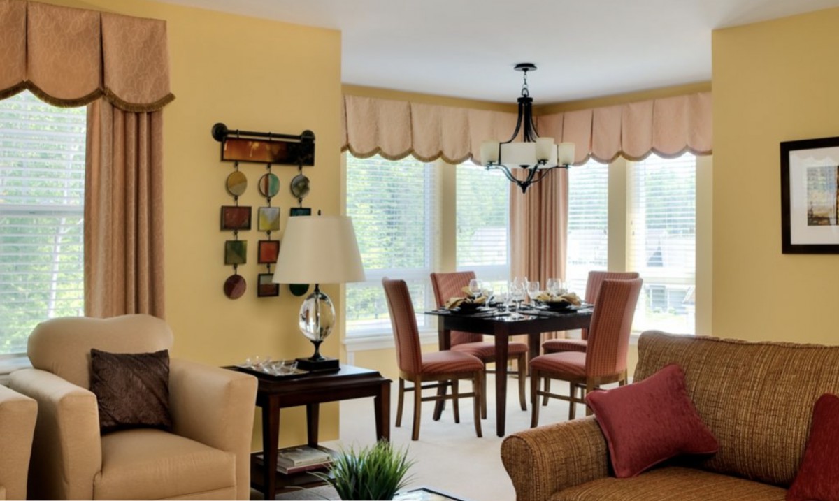 A cozy living and dining space with elegant furnishings and decor, featuring a chandelier above the dining table.