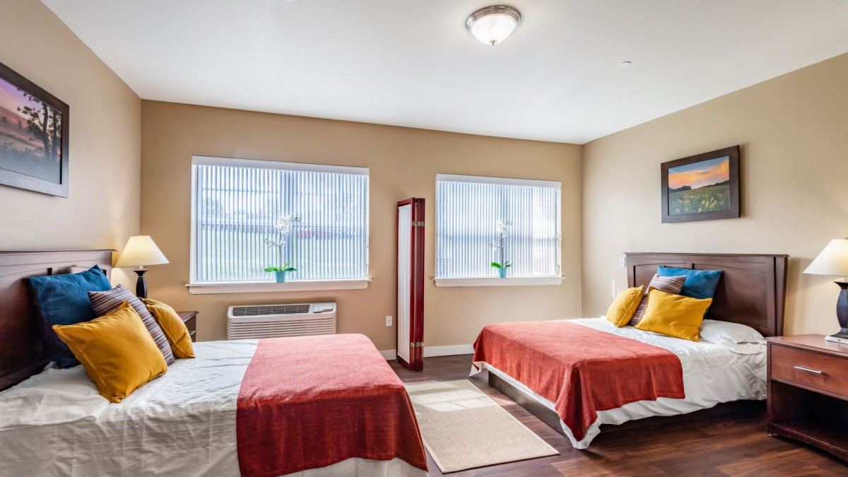 A spacious bedroom with two beds, featuring modern decor and natural light streaming through the windows.