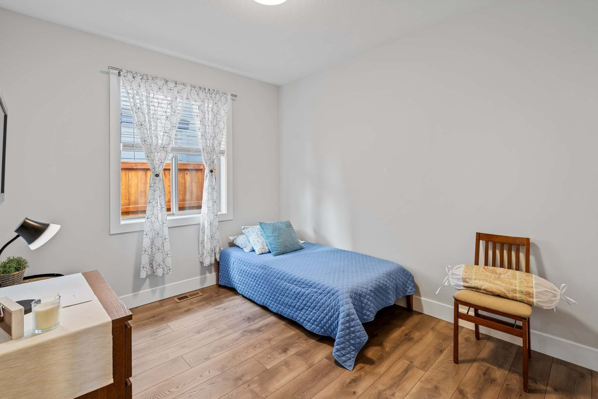 A simple bedroom with a single bed, wooden flooring, and minimalist decor.