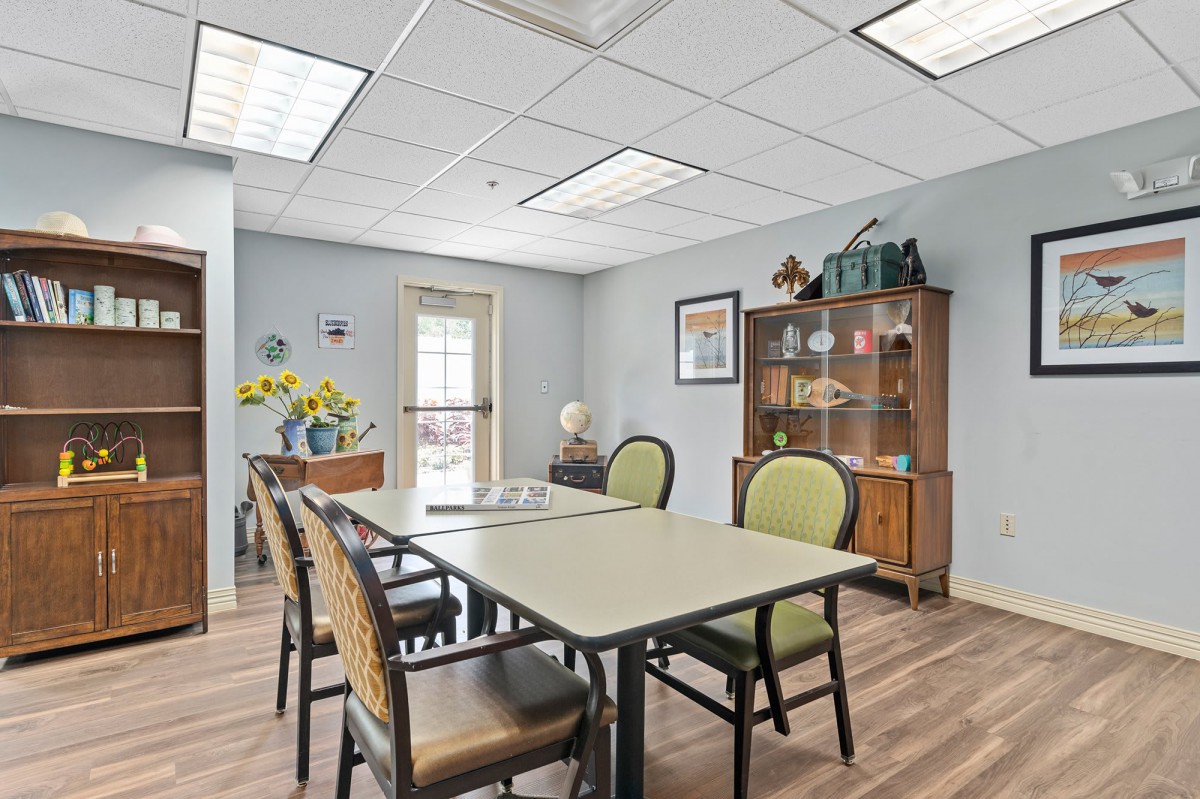 A well-lit meeting room with a table, chairs, and decorative elements such as flowers and a cabinet.