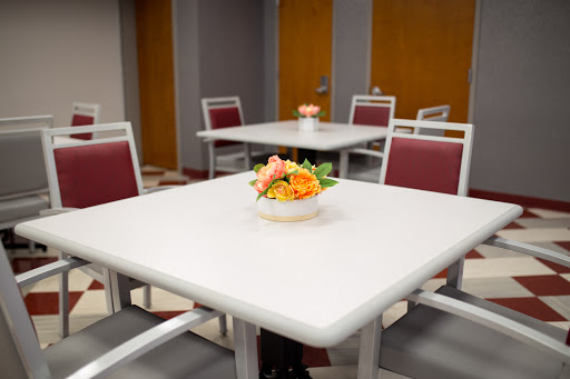 A cozy dining area featuring neatly arranged tables and chairs, adorned with a colorful floral centerpiece.