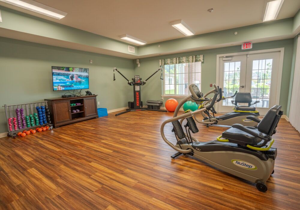 A well-equipped gym with treadmills, fitness equipment, and a television in a bright room.