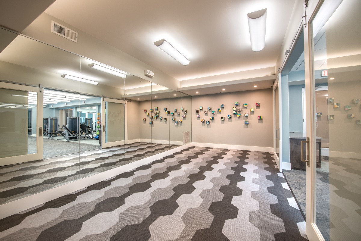 A modern yoga studio with geometric flooring and mirrored walls.