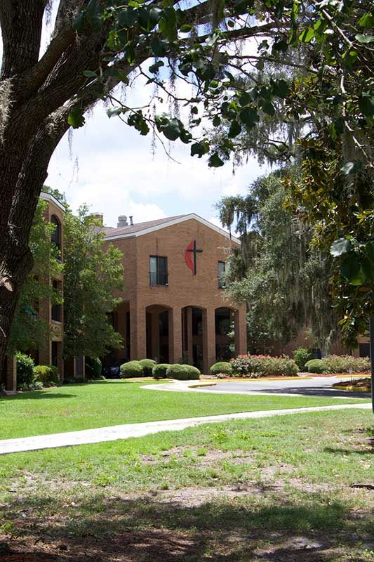 A church building surrounded by trees and a well-kept lawn.