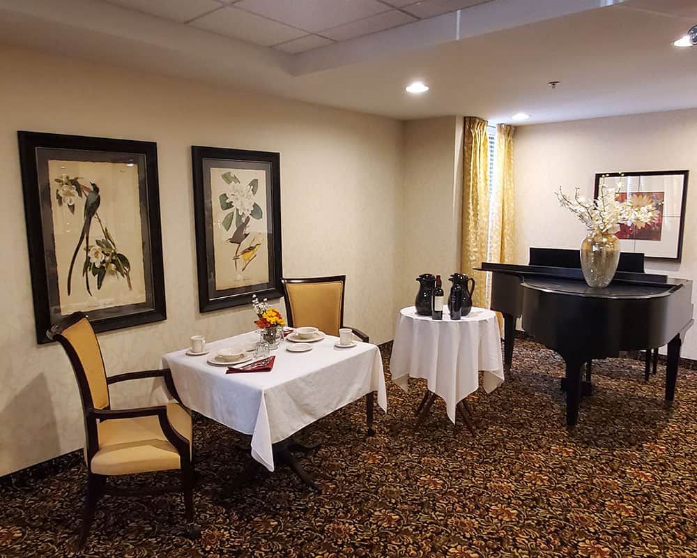 A cozy dining area with elegant decor, featuring framed artwork and a grand piano.