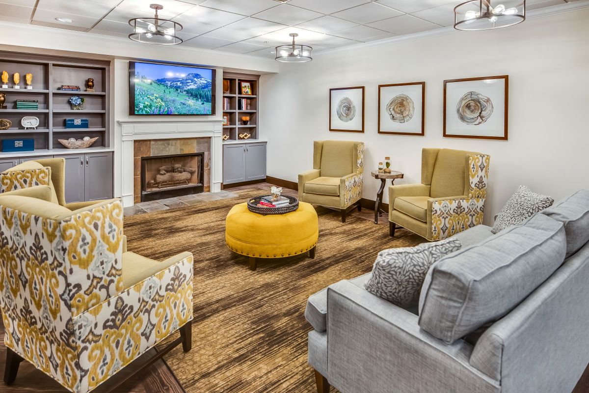 A cozy living room with a fireplace, accented with yellow furniture and wood flooring.