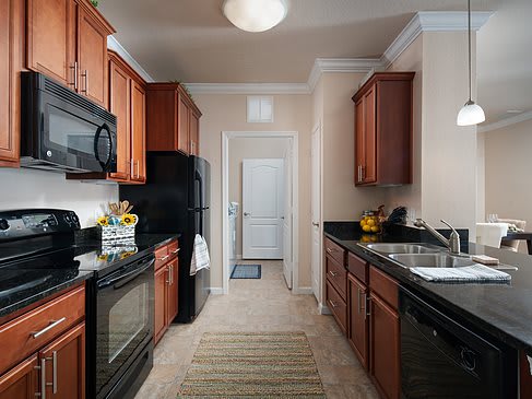 A modern galley kitchen with wooden cabinets and black appliances.
