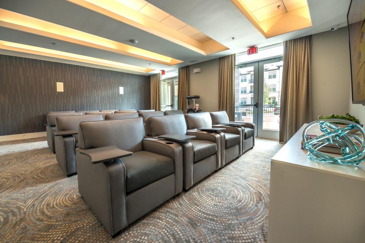 A luxurious theater room with plush seating arrangements facing a screen.