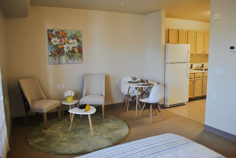 A cozy apartment with a small living area and kitchen in the background.