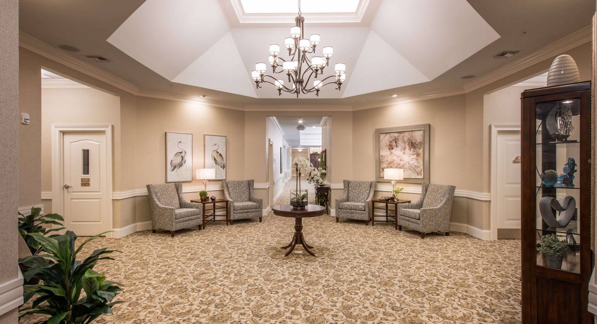 An elegant lobby featuring a central chandelier, comfortable seating, and tasteful artwork.