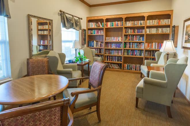A cozy library reading area with bookshelves filled with books and comfortable seating.