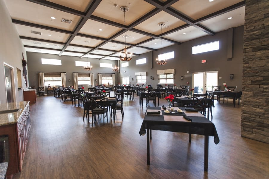 A spacious dining area with neatly arranged tables and chairs, well-lit by natural light from large windows.