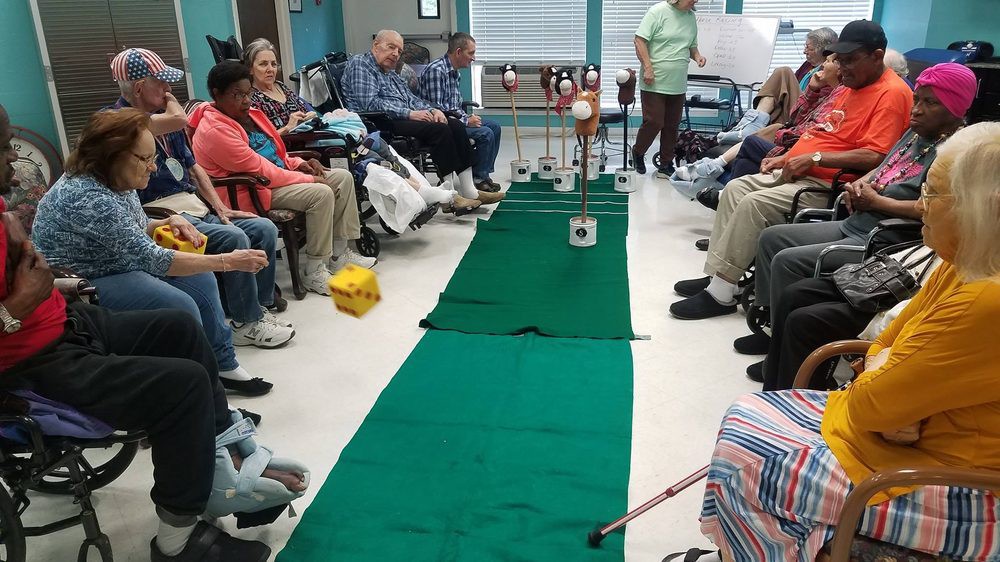 Elderly residents engage in an indoor mini-golf activity at a nursing home.
