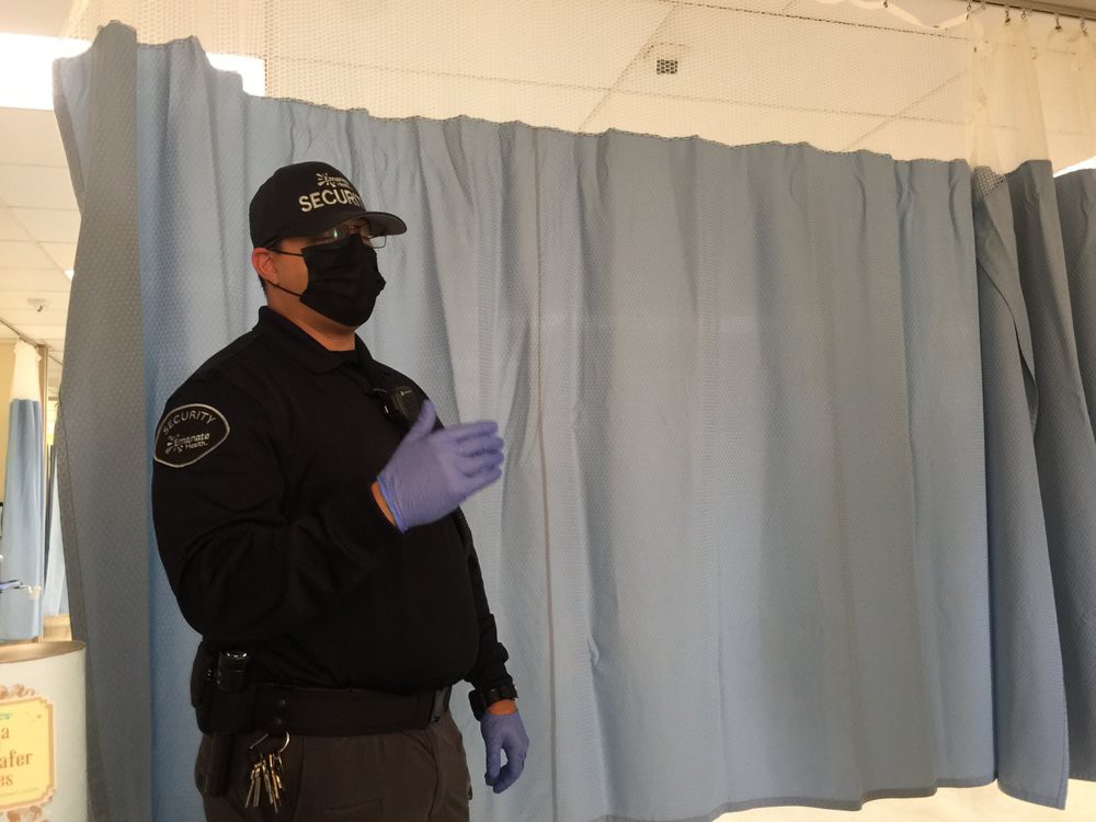 A security officer wearing a mask and gloves indoors.