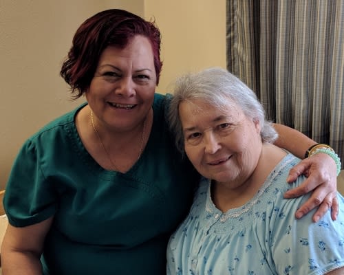Two women smiling together in a warm, friendly embrace.