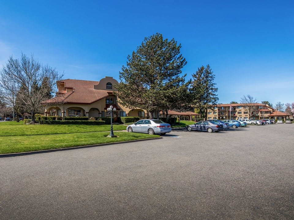 A sunny day at a residential building with a parking lot and cars.