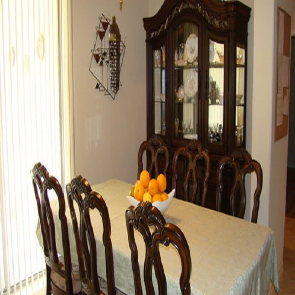 A classic dining room setup with a wooden dining table, ornate chairs, and a china cabinet in the background.