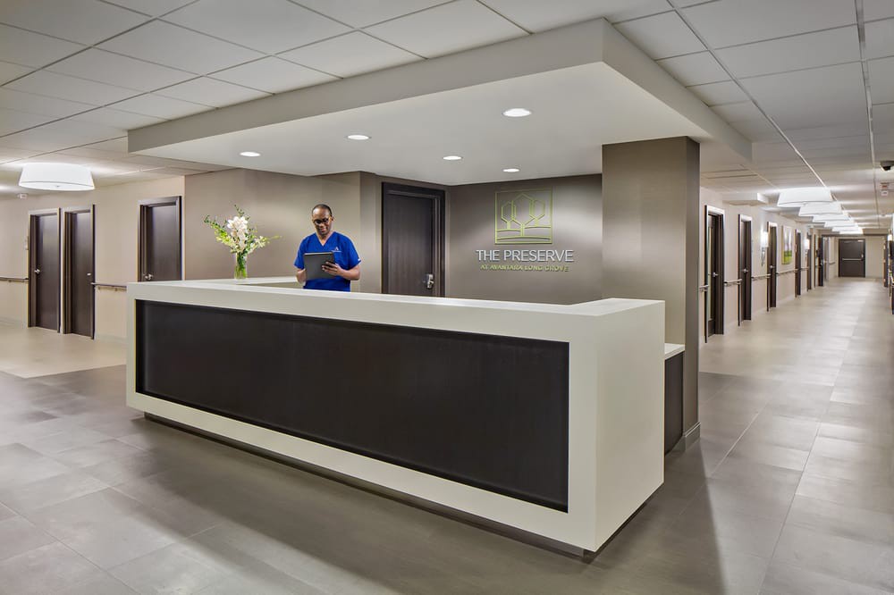 A modern office reception area with a reception desk and a person standing behind it.