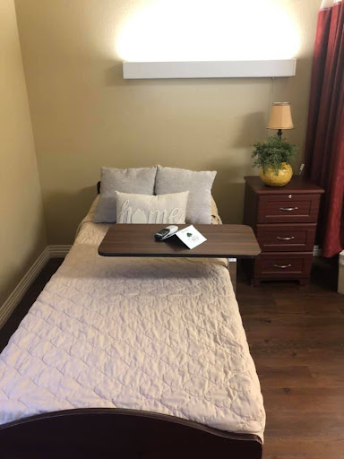 A cozy, minimalist bedroom featuring a single bed with decorative pillows and a nightstand.
