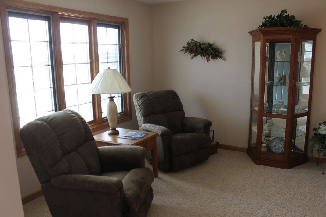 A cozy living room with two recliners, a lamp on a side table, and a decorative corner shelf.