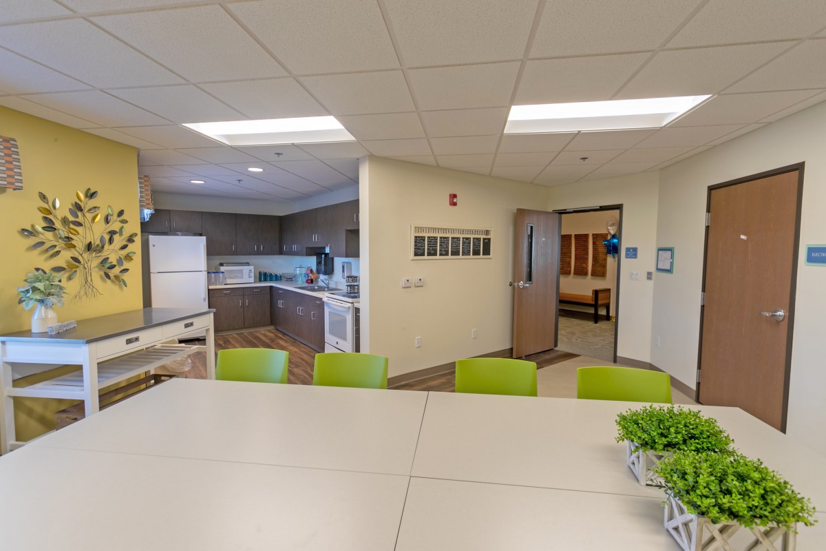 A modern kitchen and dining area with a large table and bright green chairs.