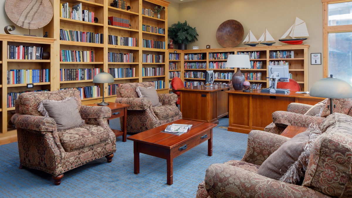 A cozy library with bookshelves, armchairs, and a coffee table.