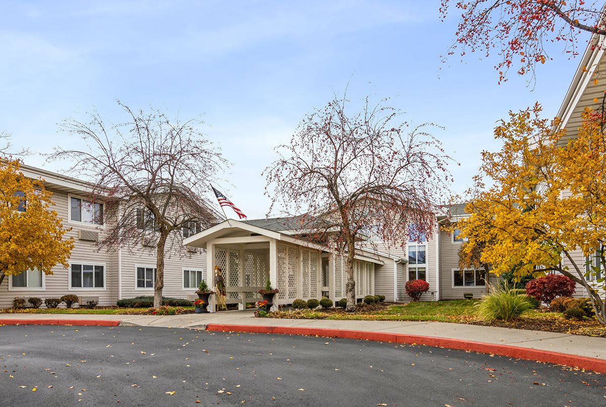 A two-story residential building with a covered entrance, surrounded by autumn trees.