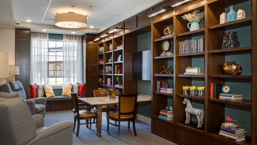 A cozy library space with wooden bookshelves and a table for reading.