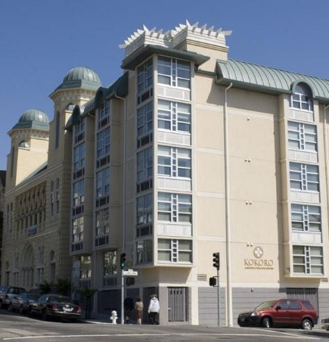 A modern urban building with cars parked along the street.