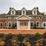 A picturesque stone and brick house with a landscaped front garden.